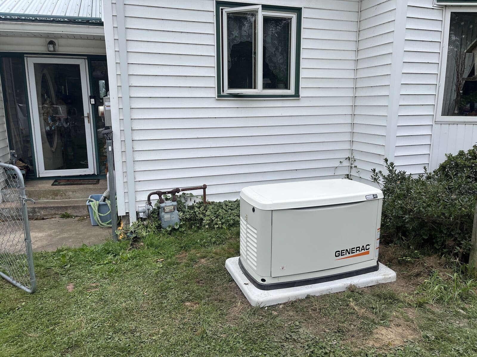 Generac generator beside a white farmhouse